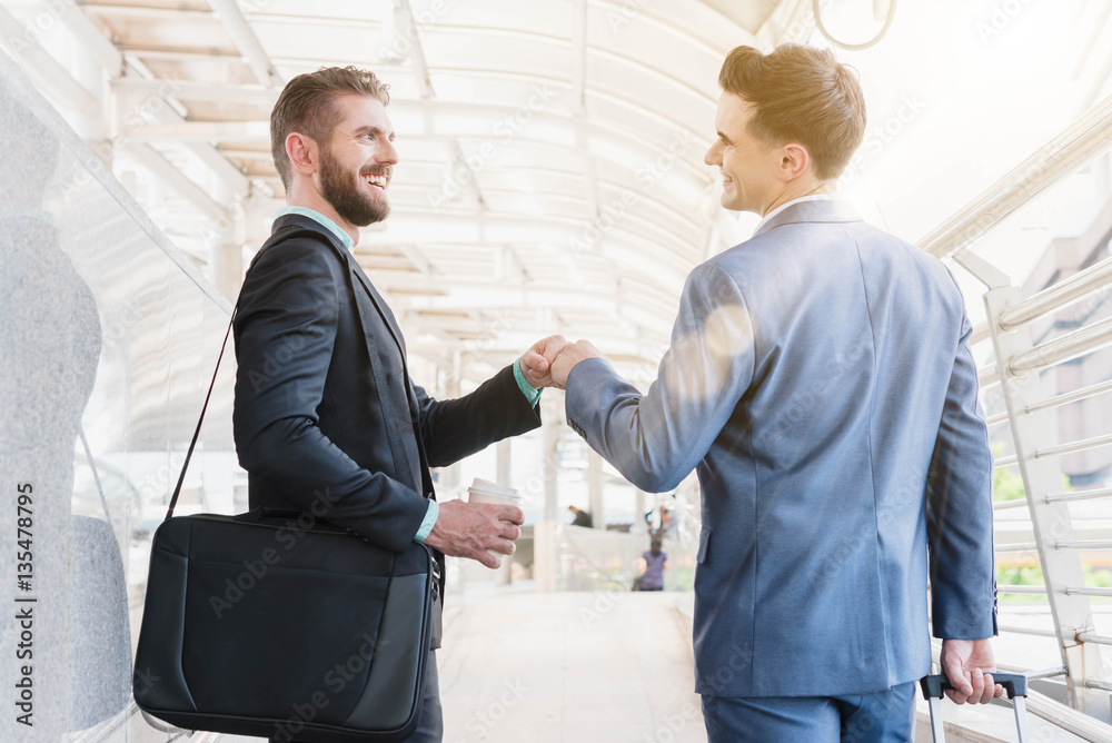 Two Westerner Business men talk and make fist bump on the public