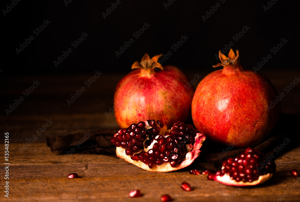 Pomegranate fruits with grains on wooden table. Dark moody. Life style.