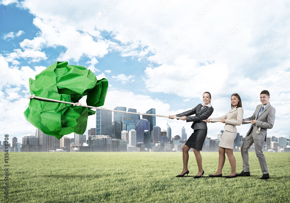 Young business people outdoors and huge paper ball as symbol of creativity