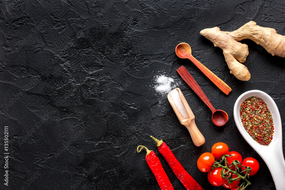 spices in wooden spoon on dark background top view