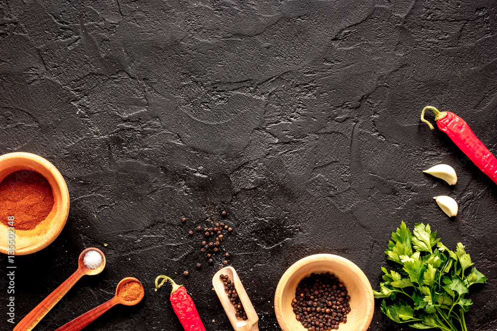 spices in wooden spoon on dark background top view