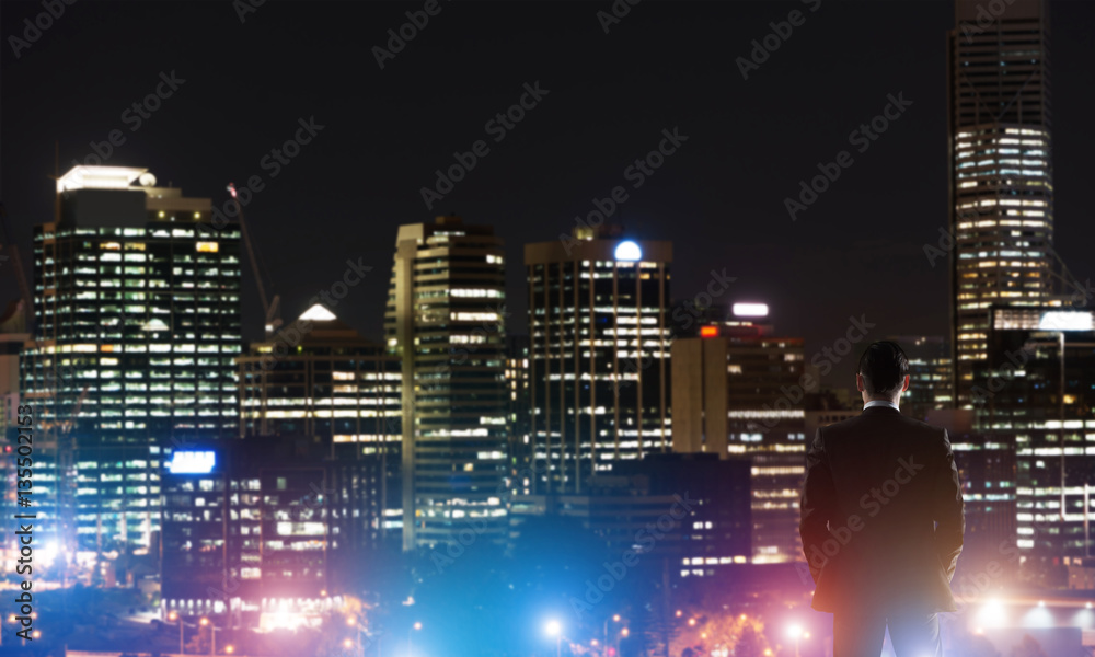 Businessman viewing night glowing city