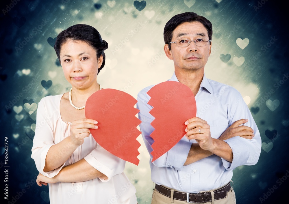 Displeased mature couple holding broken heart