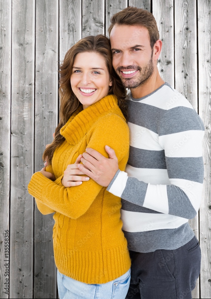 Happy couple standing in front of wooden background