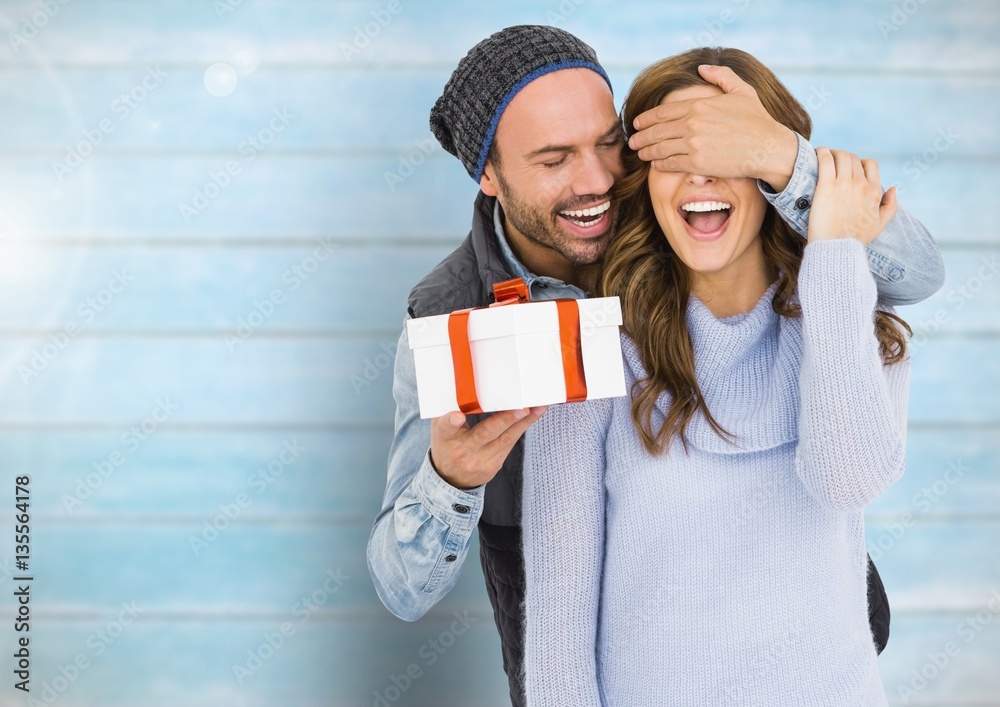 Man holding a gift box and covering eyes of woman