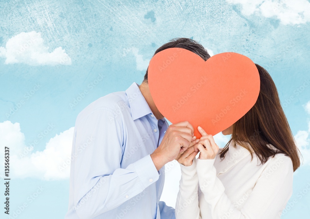 Romantic couple hiding their face behind heart