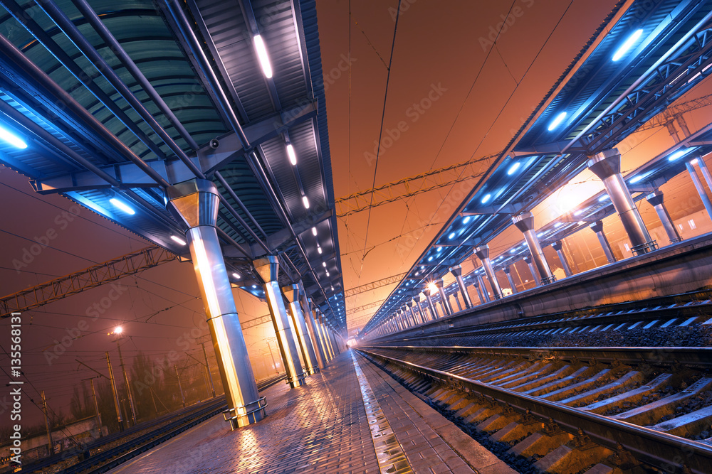 Railway station at night. Train platform in fog. Railroad