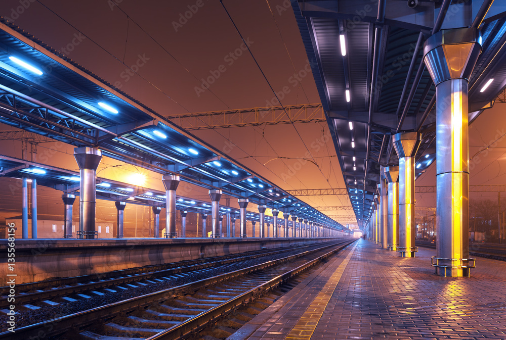 Railway station at night. Train platform in fog. Railroad