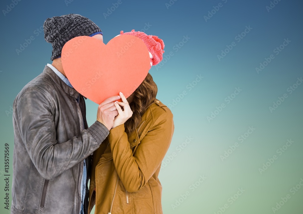 Romantic couple hiding their face behind heart