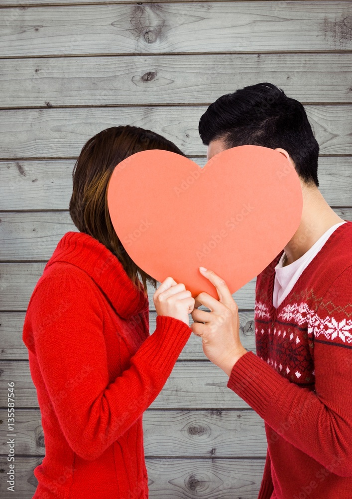 Romantic couple hiding their face behind heart