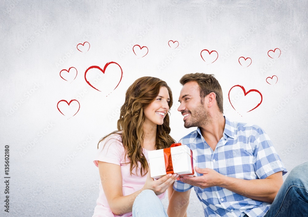 Composite image of couple with gift against hearts in background