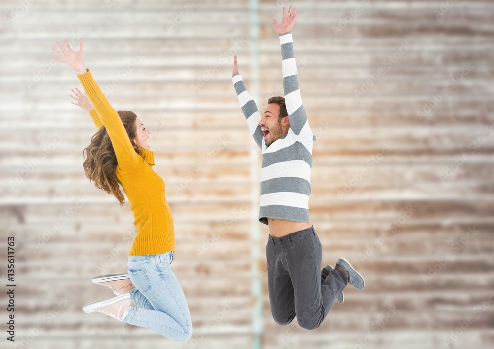 Composite image of couple jumping against bricks wall