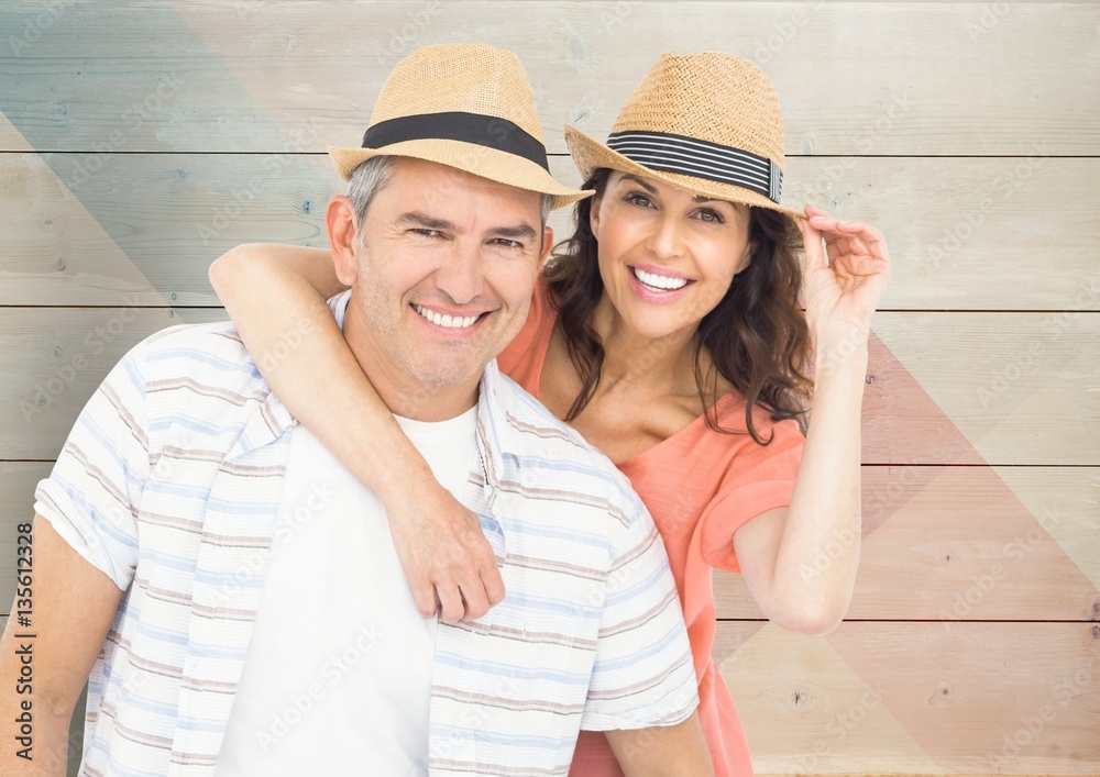 Composite image of couple with hats against wood background