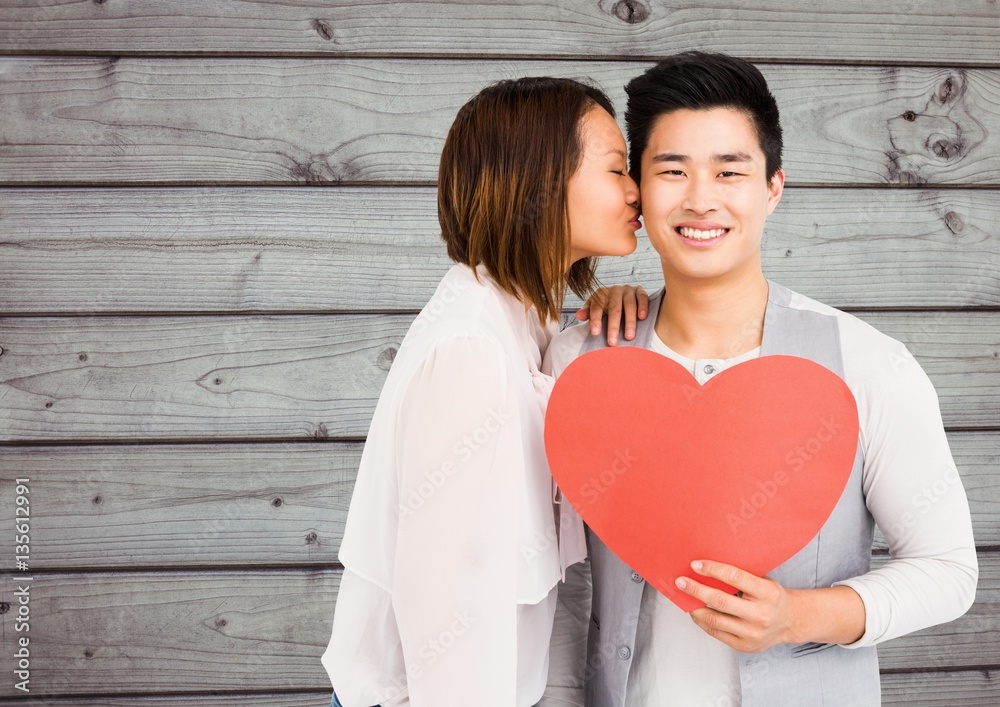 Woman kissing man holding heart