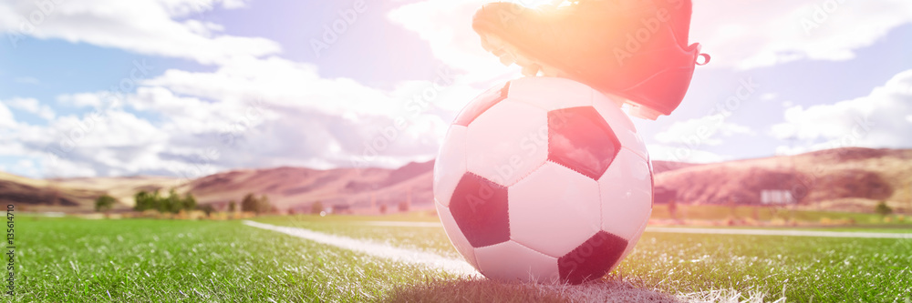 Soccer ball with player foot on soccer field