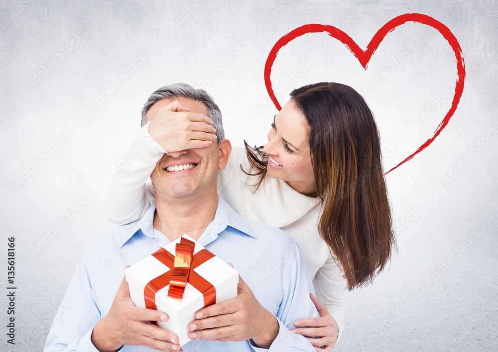 Smiling woman surprising man with a gift