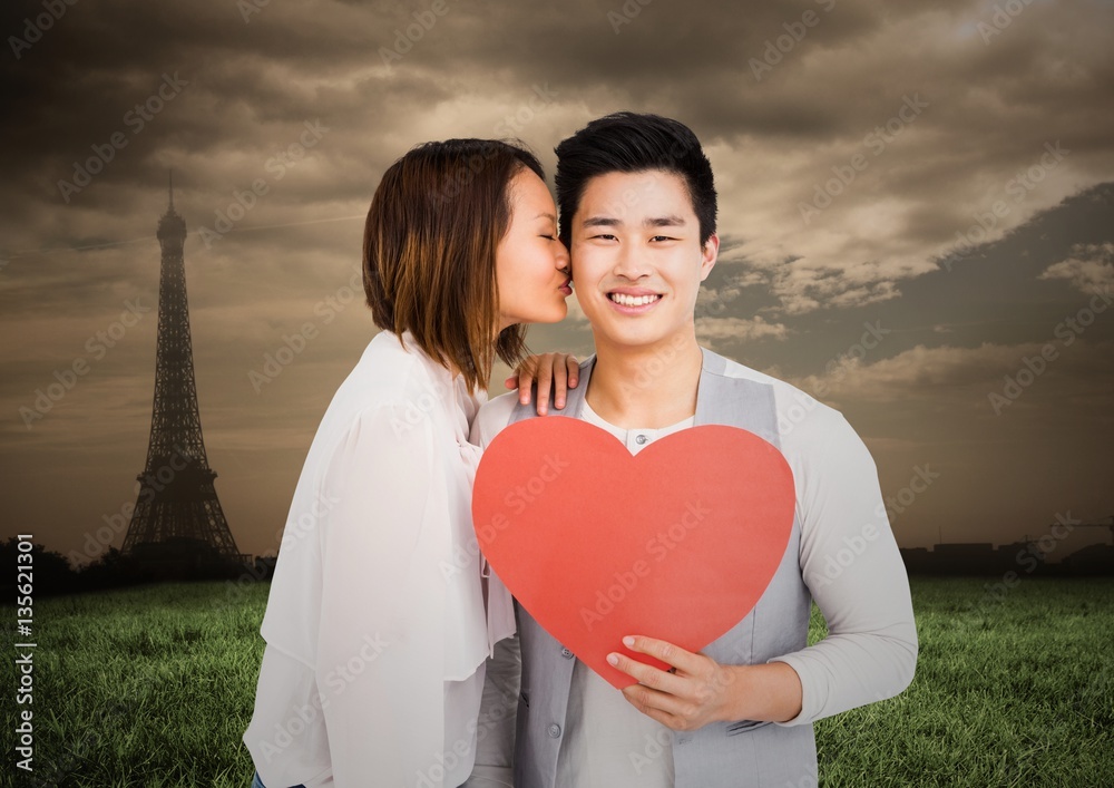 Woman kissing man while holding heart