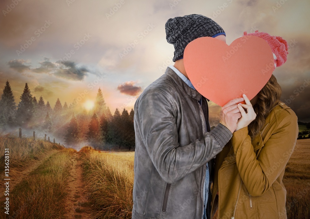 Couple hiding their face behind red heart