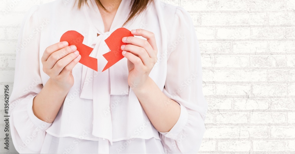 Mid-section of woman holding two broken hearts