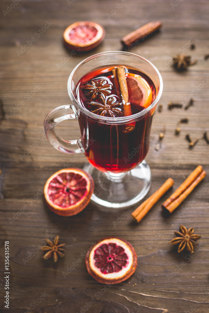 mulled wine with spices in cup on wooden background