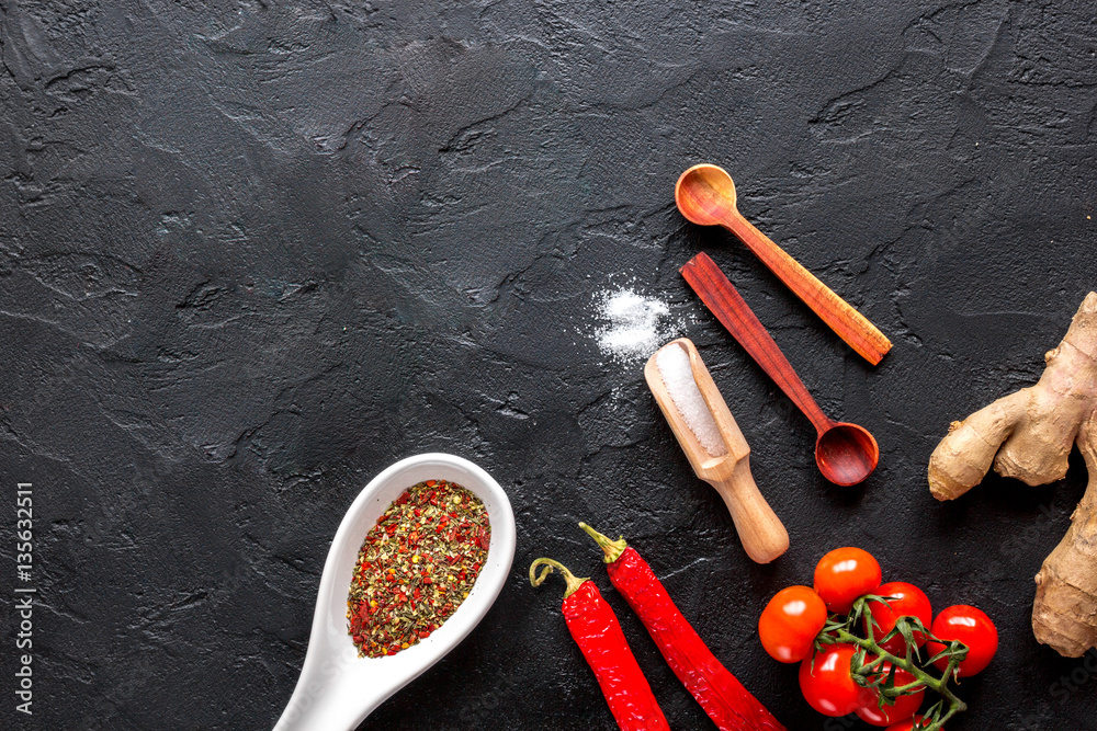 spices in wooden spoon on dark background top view