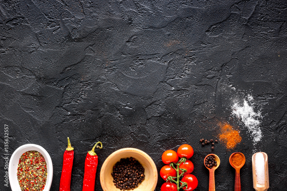 spices in wooden spoon on dark background top view