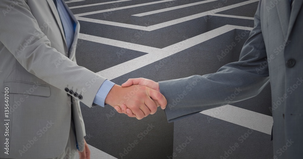 Businessmen shaking hands against maze in background