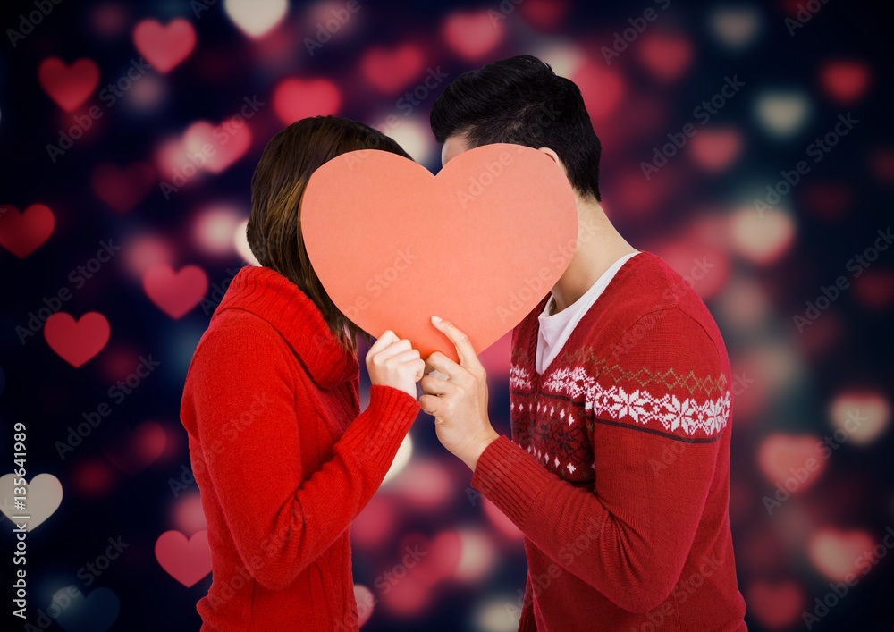 Romantic couple hiding their face behind heart