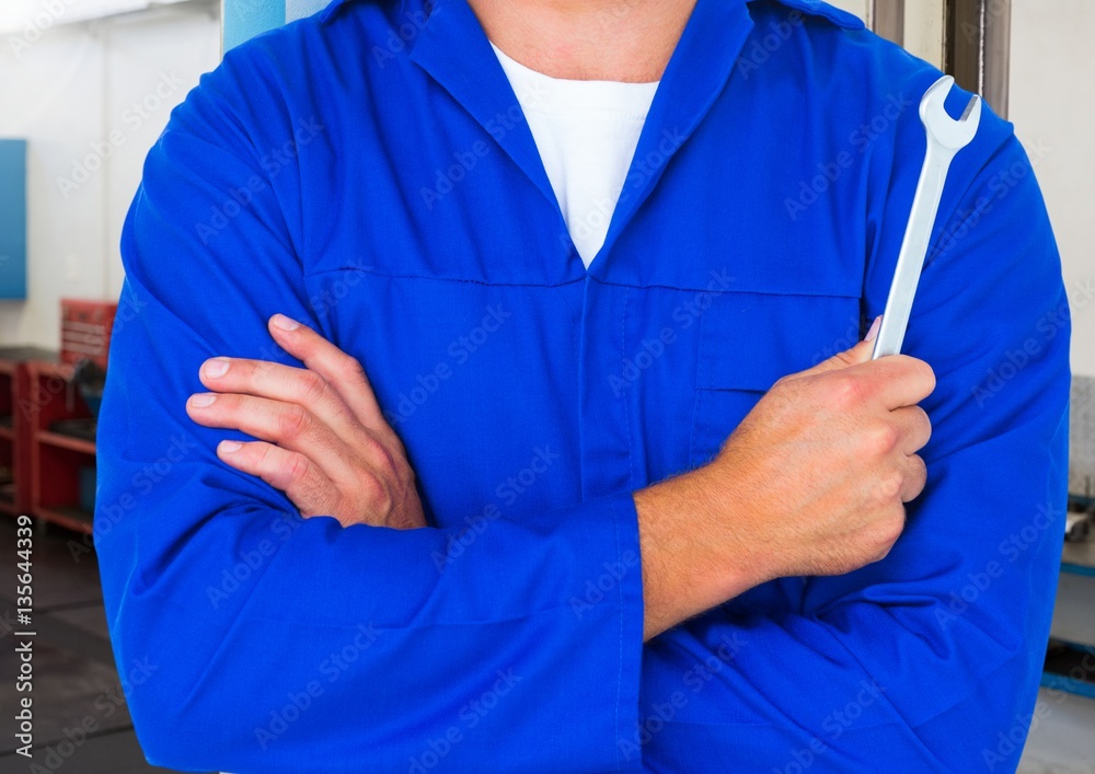 Mechanic standing with arms crossed holding wrench