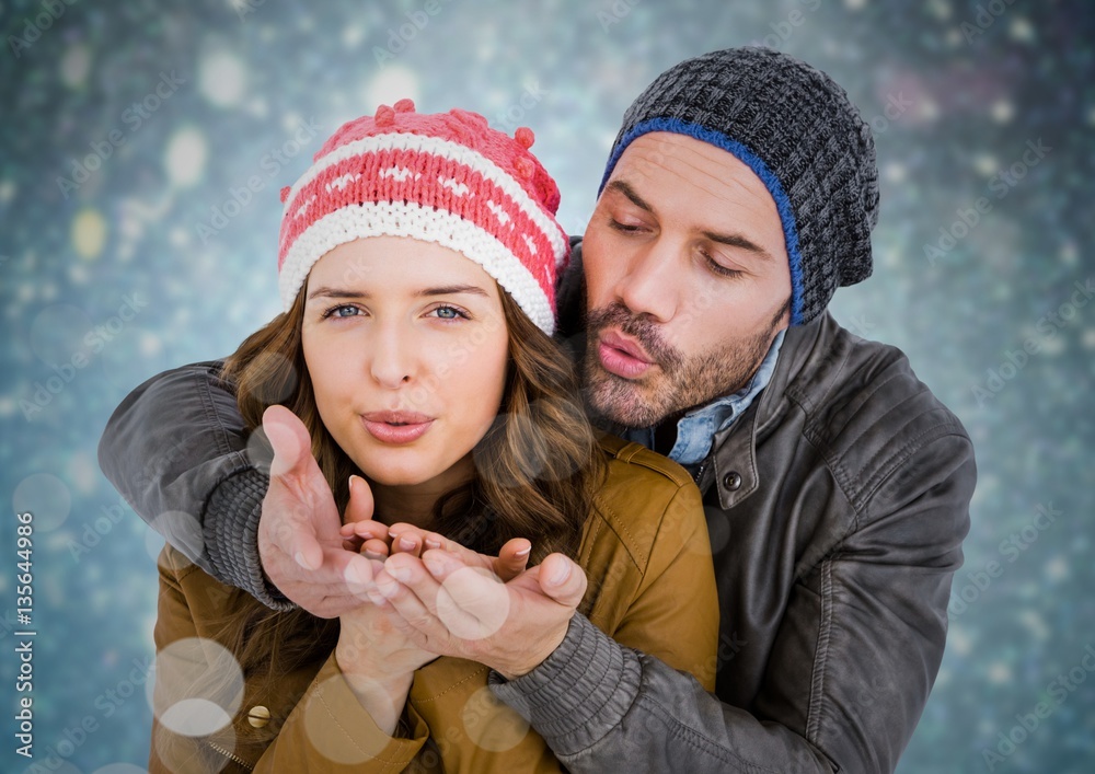 Couple blowing kisses against blue bokeh background