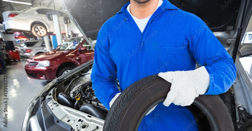 Mechanic holding tyre at garage