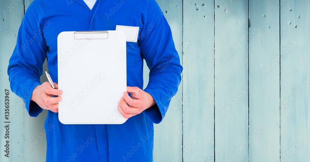 Delivery man holding clipboard against wooden background