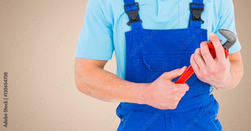 Manual worker holding a monkey wrench against beige background