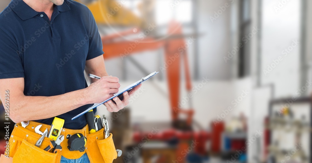 Mid section of handyman with tool belt writing on clipboard