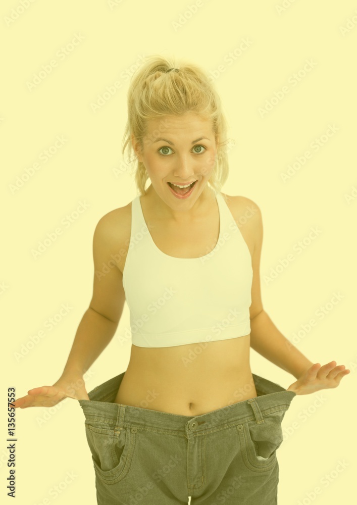 Happy woman wearing oversized pant against yellow background