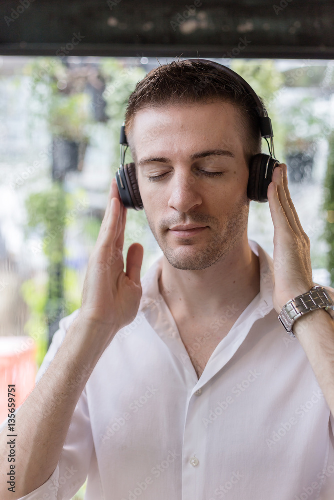 smart and handsome white man in white shirt listening music with