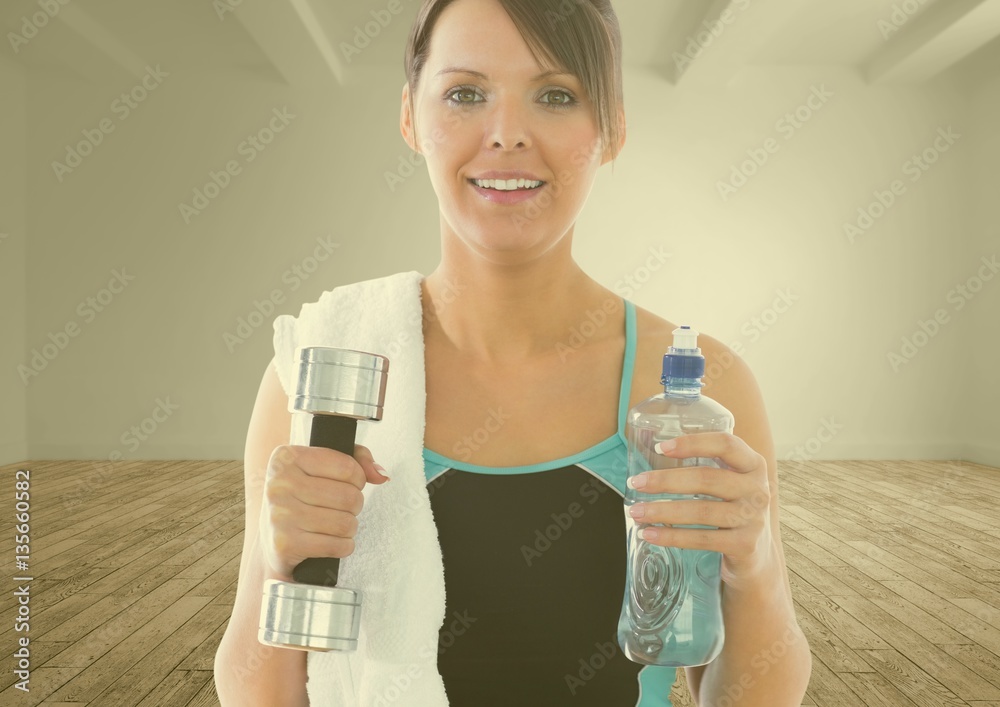 Portrait of fit woman holding dumbbell and water bottle