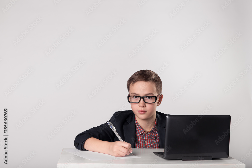 Businessman kid in spectacles writing with pen