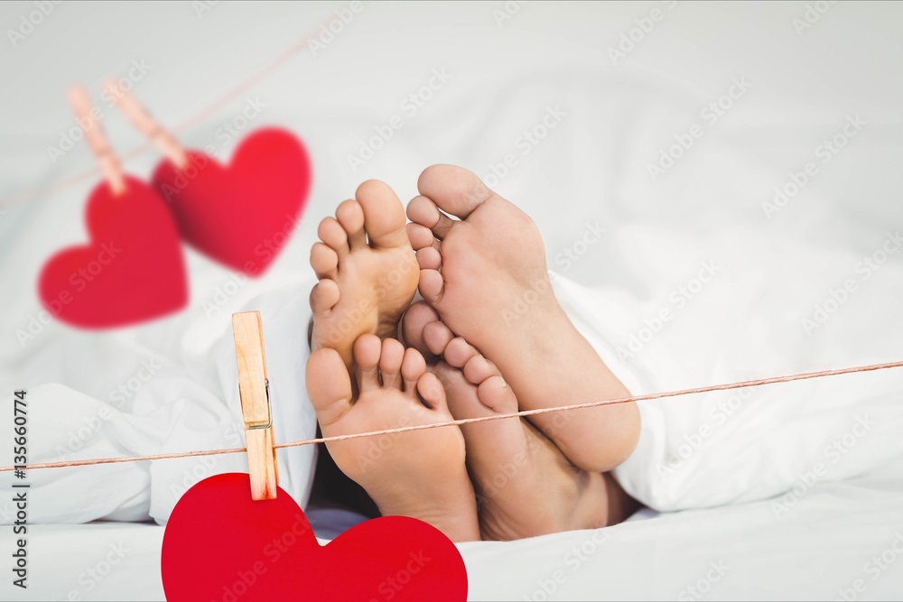 Composite image of red hanging hearts and couple lying on bed