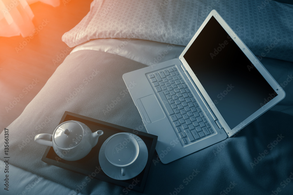 laptop on bed  with tea set on wooden tray