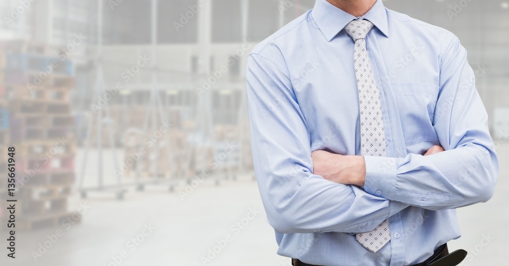 Mid section of businessman standing with arms crossed