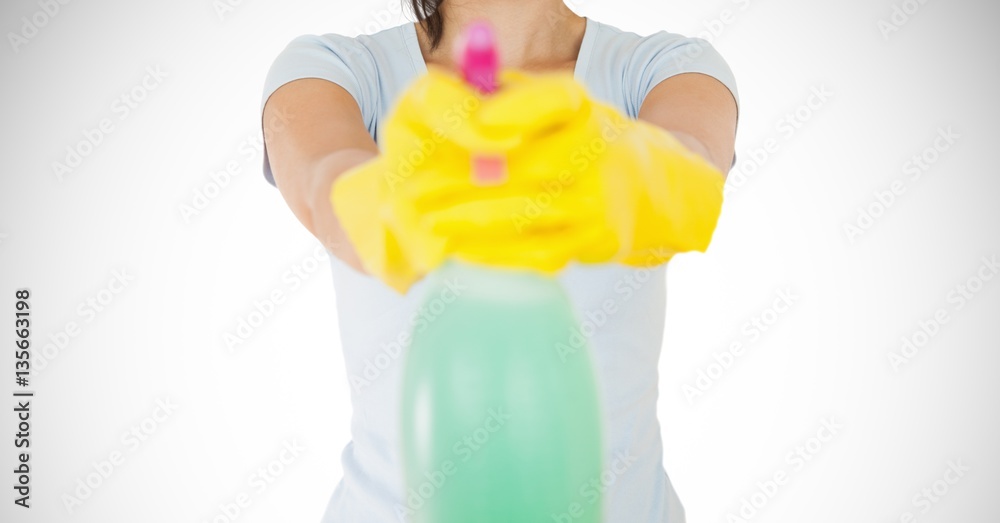 Female cleaner with yellow gloves holding a bottle