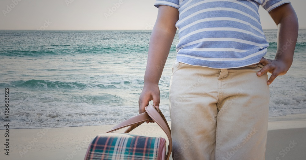 Mid section of boy holding a bag at beach