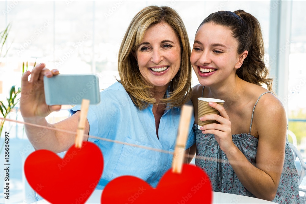 Women taking a selfie on mobile phone against red hanging hearts