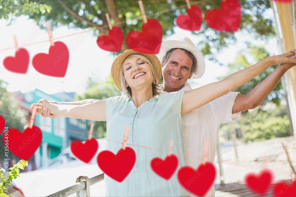 Composite image of red hanging hearts and mature couple dancing