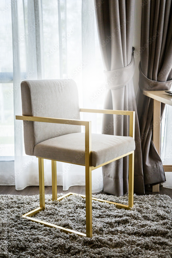 beige color upholstered chair in living room with curtain and so