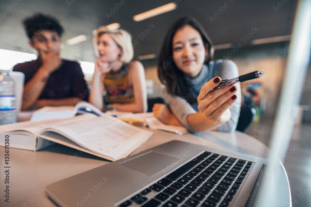 University students working on laptop in a library