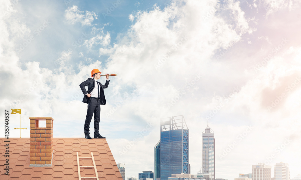 Engineer man standing on roof and looking in spyglass. Mixed med