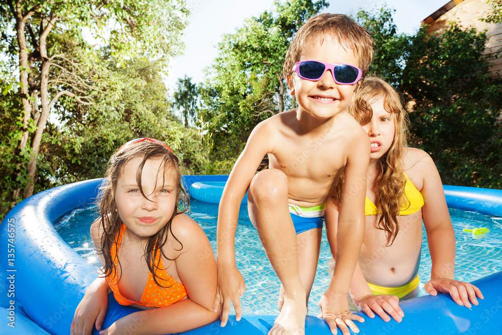 Three happy kids having fun in swimming pool