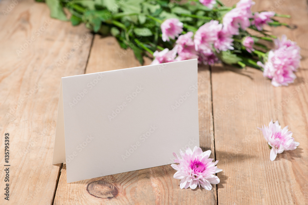 Pink flowers and empty paper for your text on wooden background